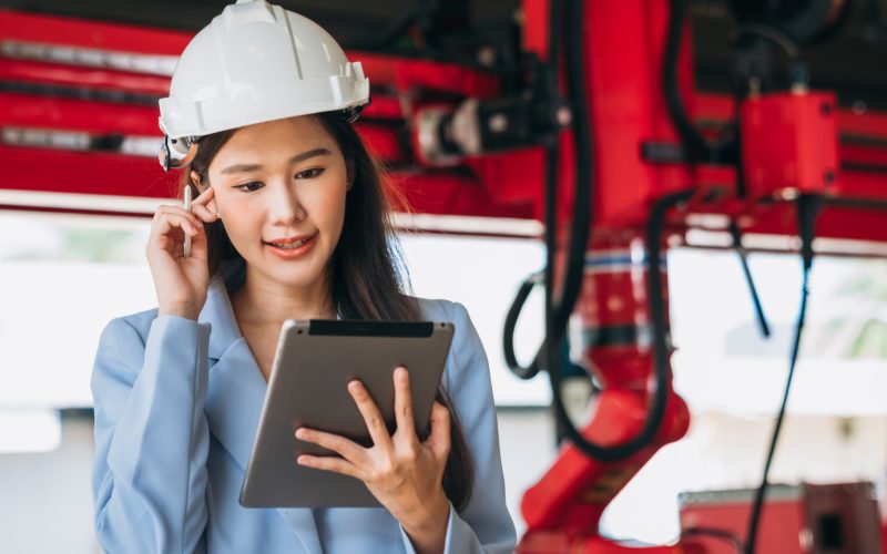 Portrait of Engineers inspecting and check up machine of the automated arms machine welding robots at factory machines. Technician working with tablet in manufacture industrial.